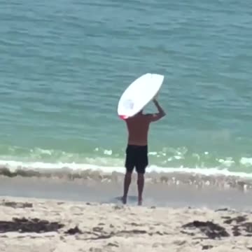 Man lifting his white surf board on beach