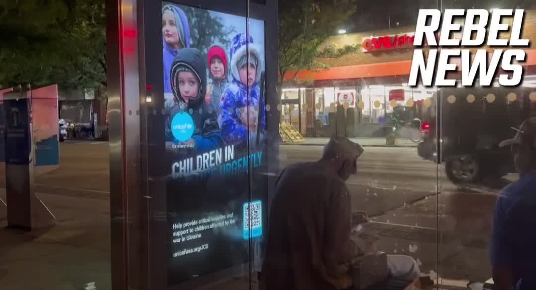 Homeless Man Eats Next to a "Ukraine Needs Your Help" Sign