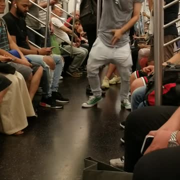 Guy in grey head phones on train dancing