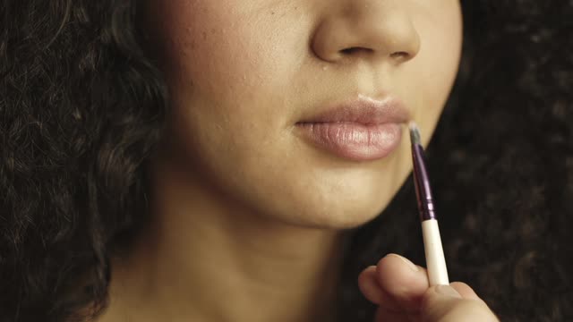 A beautiful girl doing makeup on the lips