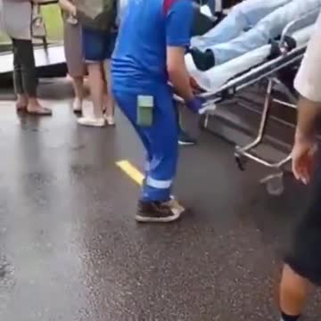 Citizens Wait in Line for the COVID “Vaccine” After a Man Is Transported by Stretcher