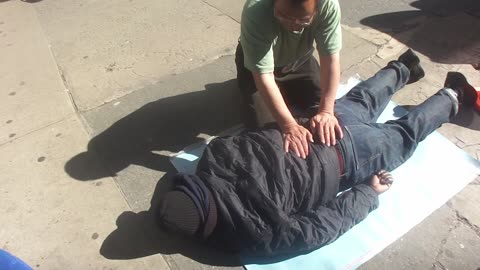 Luodong Massages Black Man's Back On Sidewalk