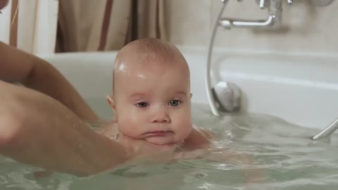 Mother bathing her baby in the tub