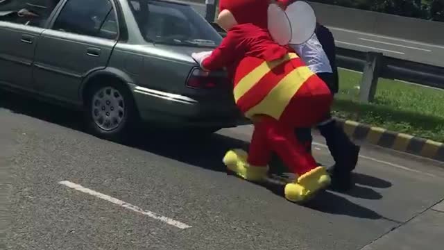 Mascot helps push broken vehicle