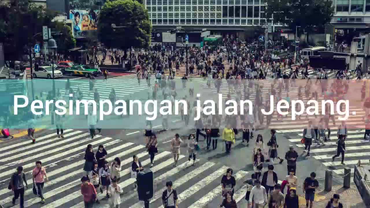 Crowds of people cross a street junction