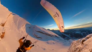 Paraglider Flies and Skis Over Golden Hour Mountains