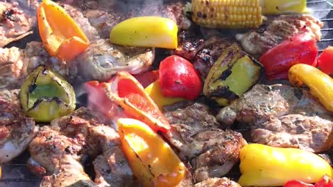 Man Prepares Vegetables and Meat Over Barbeque