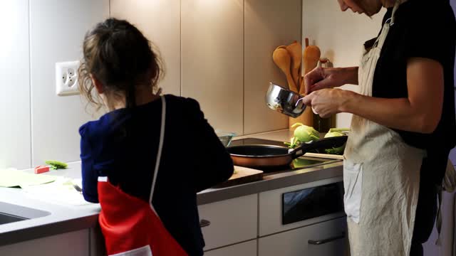 A Mother Getting Assistance From Her Young Daughter In Preparing a Meal