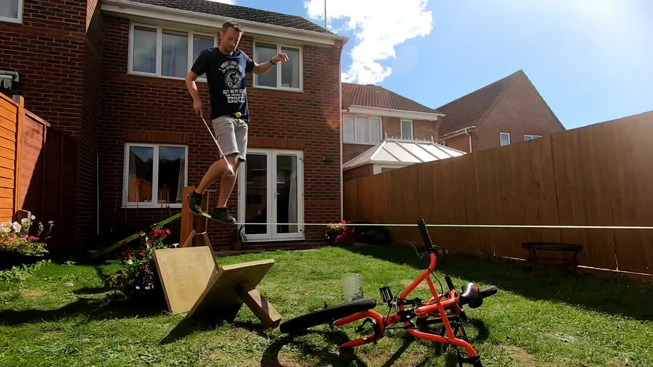 Guy Juggling a Golf Ball While Balancing On a Slackline