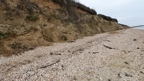 Hiking . Vlog on a beach with a cliff face .