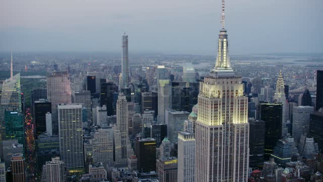 The empire state building and city skyscrapers glow at dusk