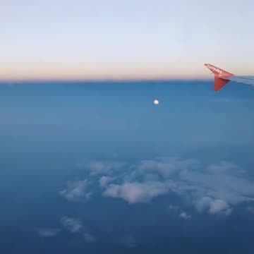The local moon below the airplane sitting among the peaceful clouds. 🌝