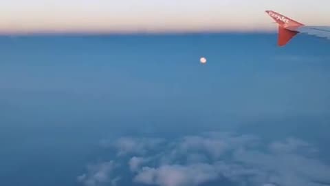 The local moon below the airplane sitting among the peaceful clouds. 🌝