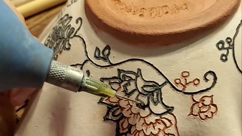 Applying undeglaze to a carved bowl