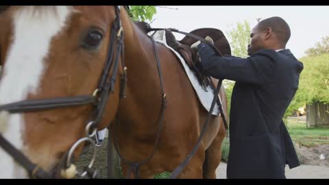 African American man installing the horse saddle