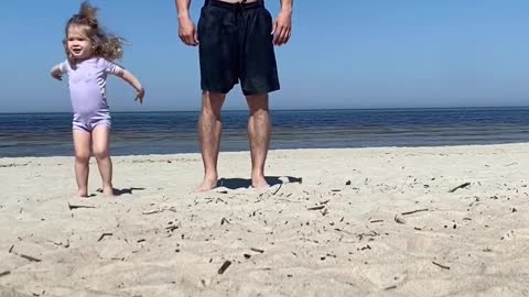 Little Girl on Beach Tries to Workout With Father