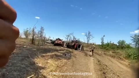 Ukrainian soldiers transporting water to their comrades through a column of wrecked vehicles