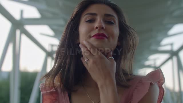 A model caresses her face as she poses on a pedestrian bridge