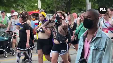 Black leather muzzled person at Toronto trans march walks in front of kids