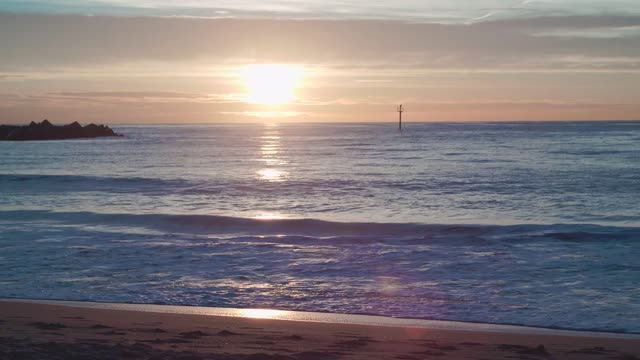 The sunset sea is beautiful on the beach with spray.