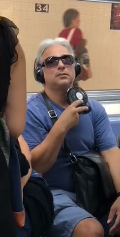 Man blue shirt uses a personal fan