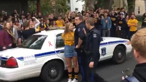 Teen girl in yellow shirt is being arrested by police, crowd chants