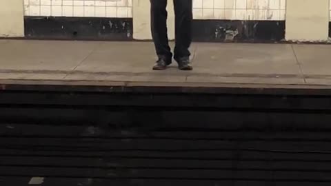 Man in grey shirt and tie singing in subway station