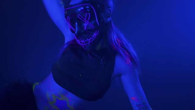 Young woman dancing with a mask under a party light