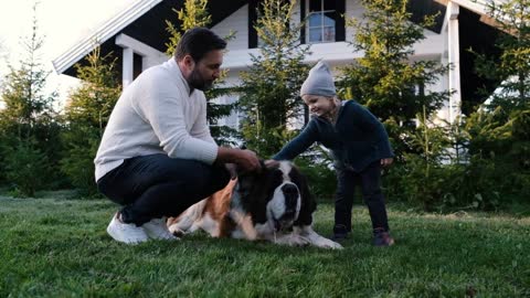 Happy family dad and son play with their big dog near the house in nature