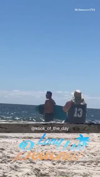 Guy with blue surfboard walking around on beach