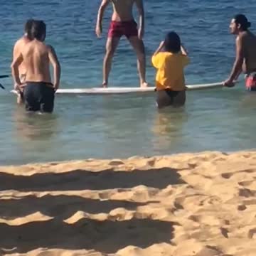 Man in red shorts stands on surf board in ocean