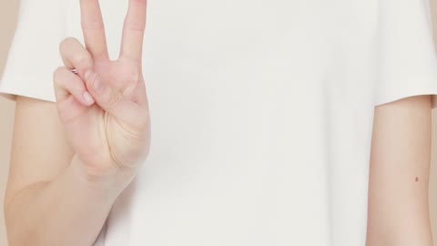 A Woman Wearing White Shirt while Doing Peace Sign