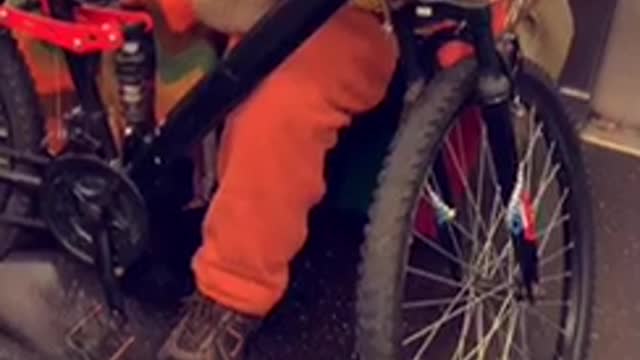 Man in orange outfit brings his bike on subway train