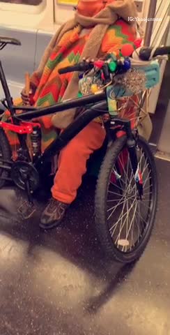 Man in orange outfit brings his bike on subway train