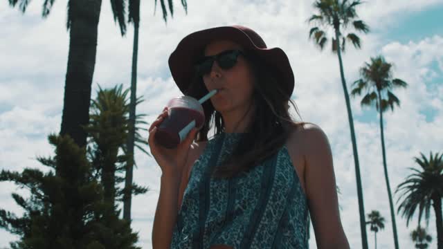 A woman walking and drinking a smoothie