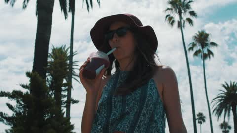 A woman walking and drinking a smoothie