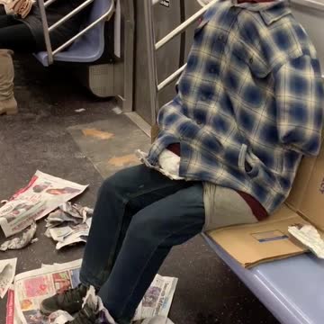 Clothes stuffed with pillows, looks like person sitting on subway, no head
