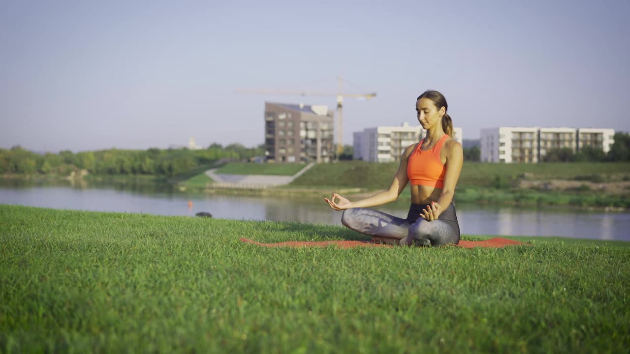 Woman meditating on the park by the river