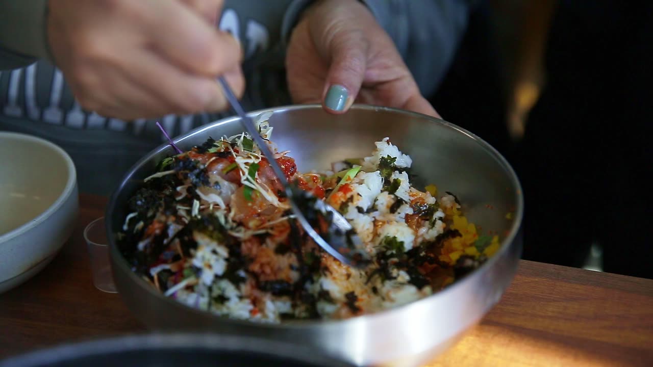 The hand of a person who is mixing bibimbap, Korea's representative food