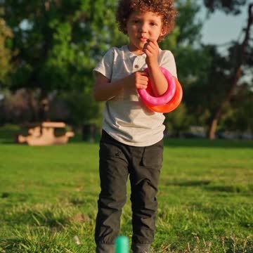 Boy Running In A Field With A Toy Wooden Airplane In His Hands At Sunset