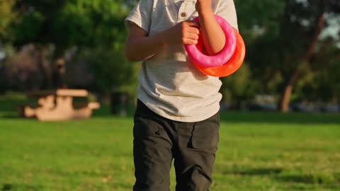 Boy Running In A Field With A Toy Wooden Airplane In His Hands At Sunset