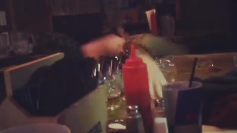 Guy in black shirt falling off table and spilling drinks