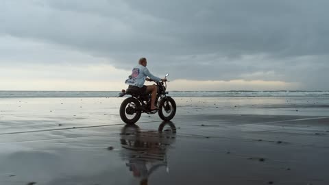 Man riding motorcycle on the beach on a cloudy day