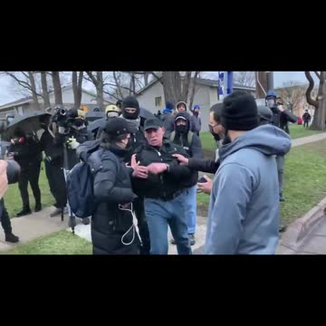 Protesters throw a water bottle at a CNN crew membe