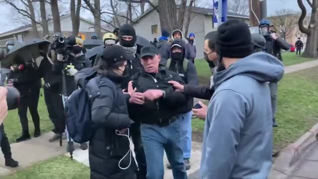 Protesters throw a water bottle at a CNN crew membe