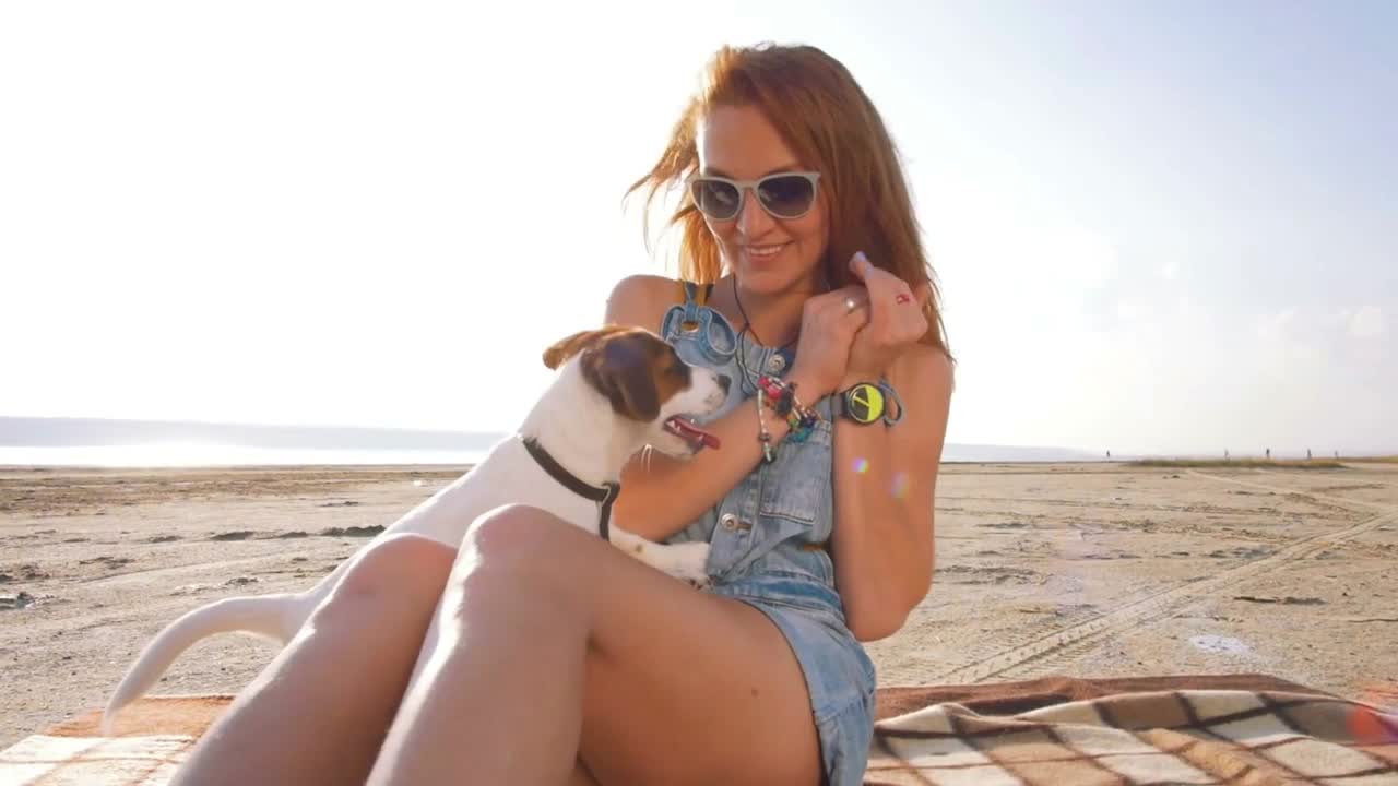 young stylish hipster playing dog puppy jack russell on the beach