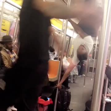 Performer on subway train uses pole to walk and spin around on the roof, "pyt" dance