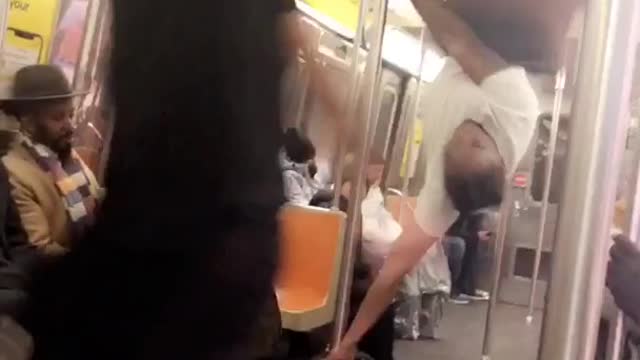 Performer on subway train uses pole to walk and spin around on the roof, "pyt" dance