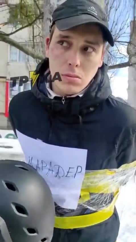 Ukriane: young man tied to poles with sign taped on jacket