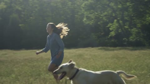 girl running through field with dog